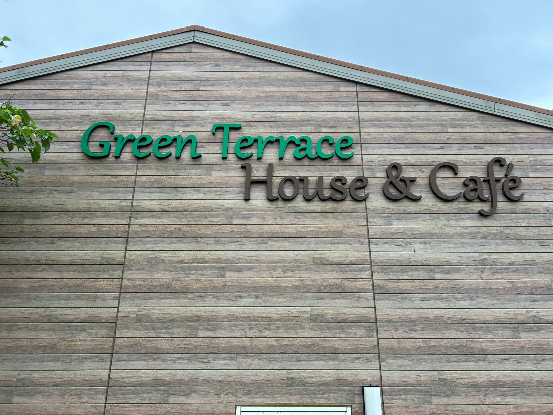 緑の板壁に「Green Terrace House & Café」の立体文字が付いた建物外観